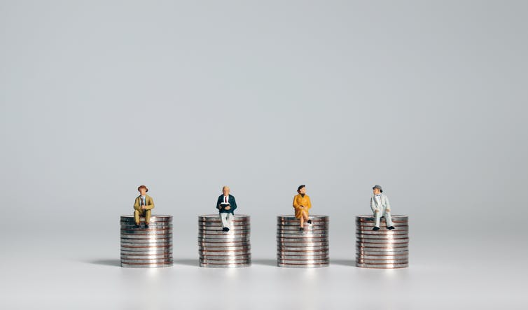 Four piles of coins with small figurines of people sitting on top of them.