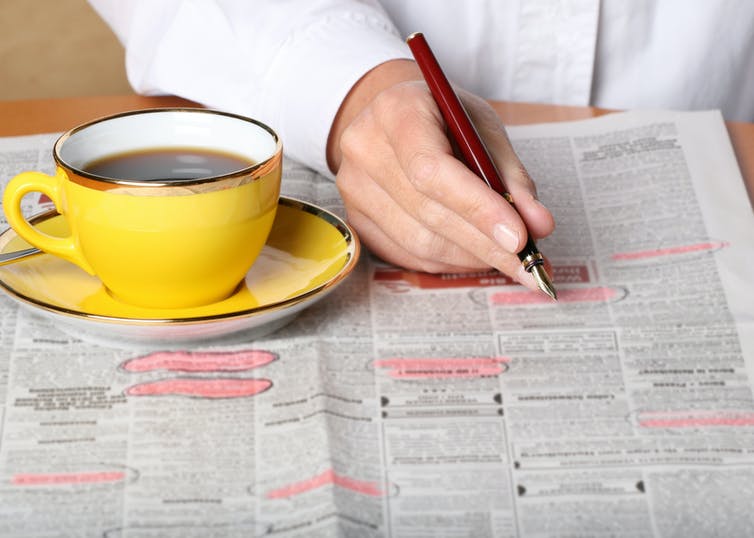 Woman circling job advertisements in the newspaper