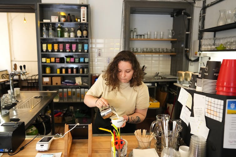 A barista preparing a coffee behind the counter of a coffee shop