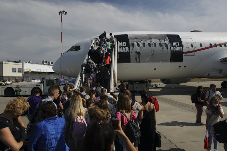 A line of people wait to board a plane