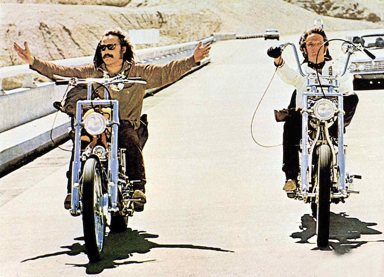 Two men ride motorcycles on the highway.