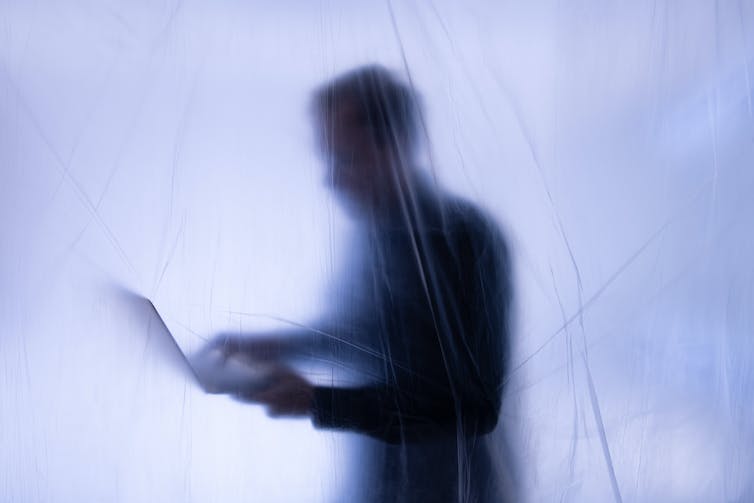 A silhouette of a man typing on a computer screen