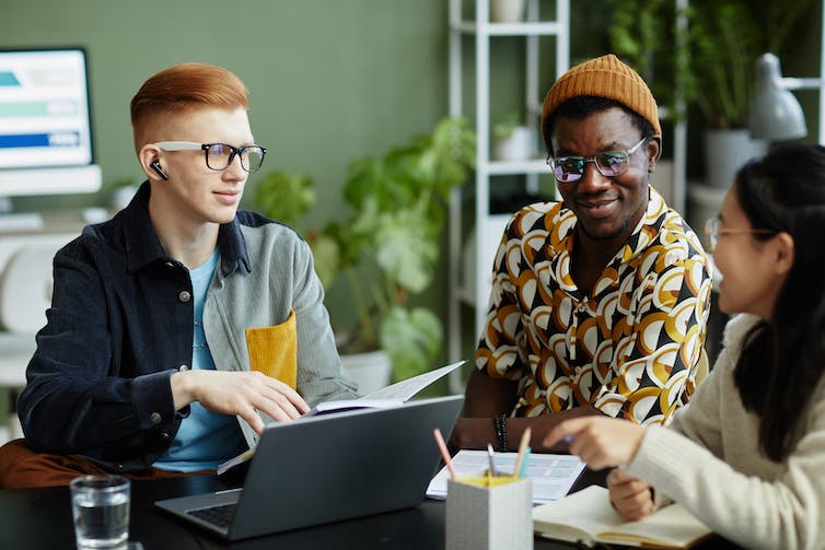 A group of young adults sitting and chatting in an office