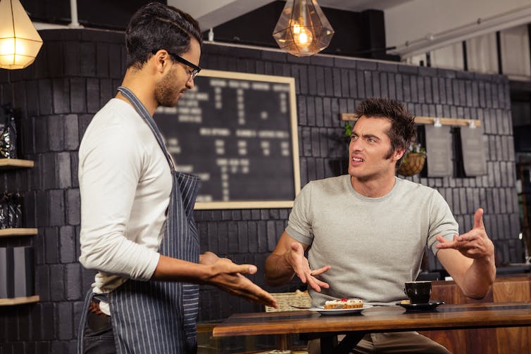 photo man at a cafe speaking angrily to a waiter