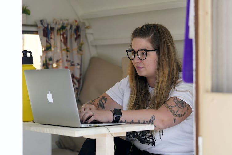 A woman works on a laptop at a table inside a camper