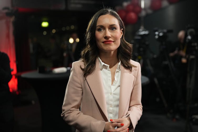 A woman in a suit jacket and dress shirt looks off-camera