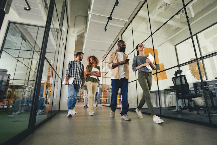 Group of young professionals walking with laptops in an office