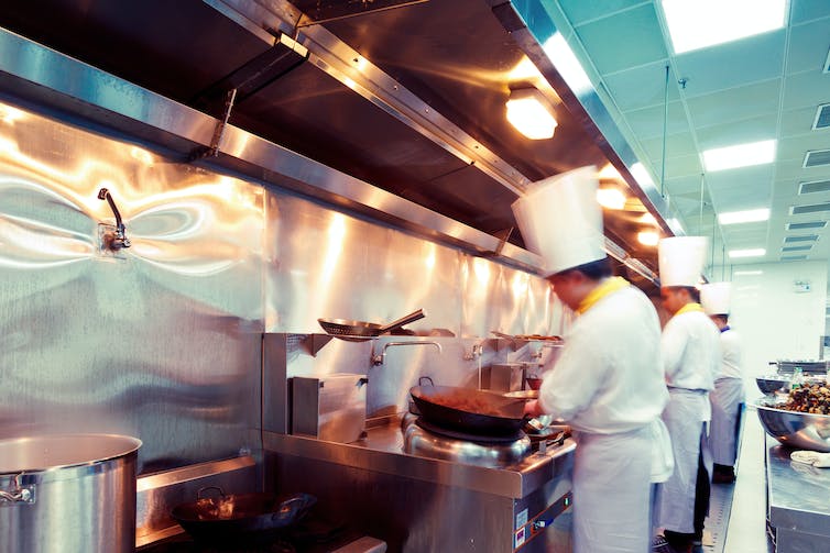 People in white chef uniforms working in a restaurant kitchen