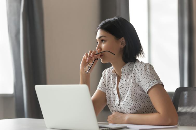 An anxious-looking woman sits at a desk.