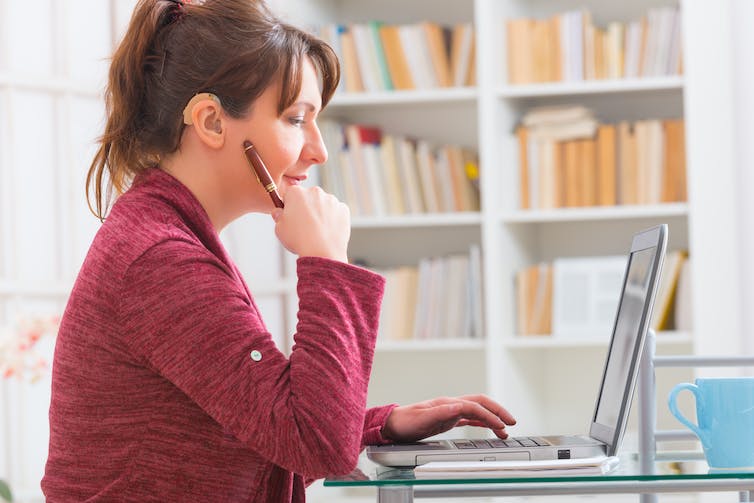 A woman with hearing aids working at a computer