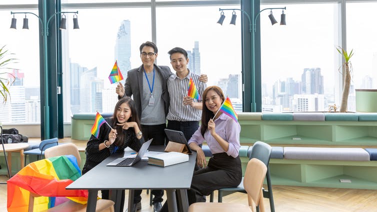 A group of people in business clothing holding pride flags