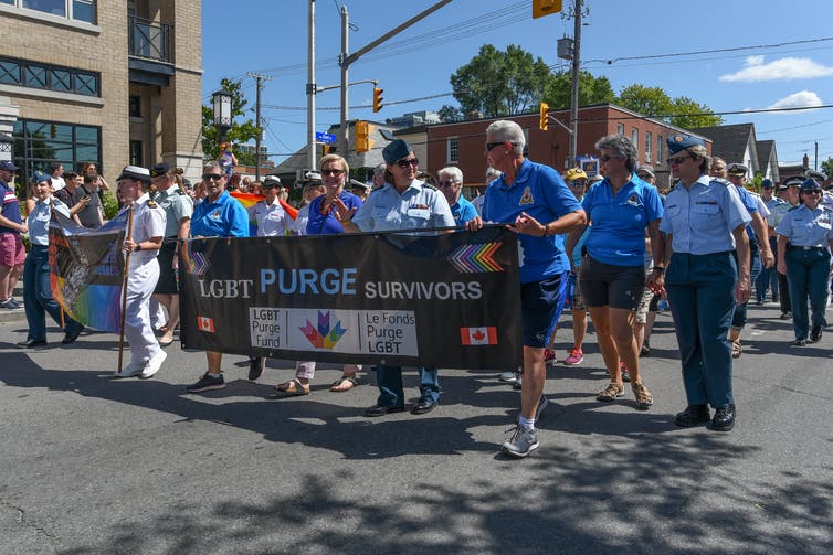 A group of people in marching in a parade holding a bannar