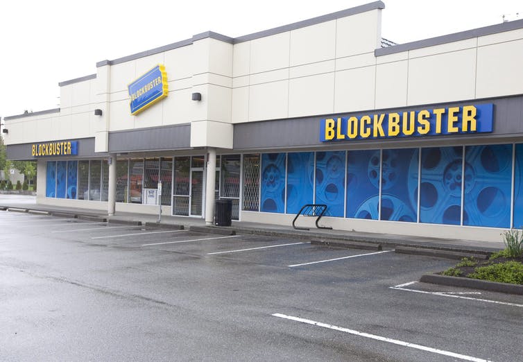 A building in an empty parking lot that says BLOCKBUSTER across the front