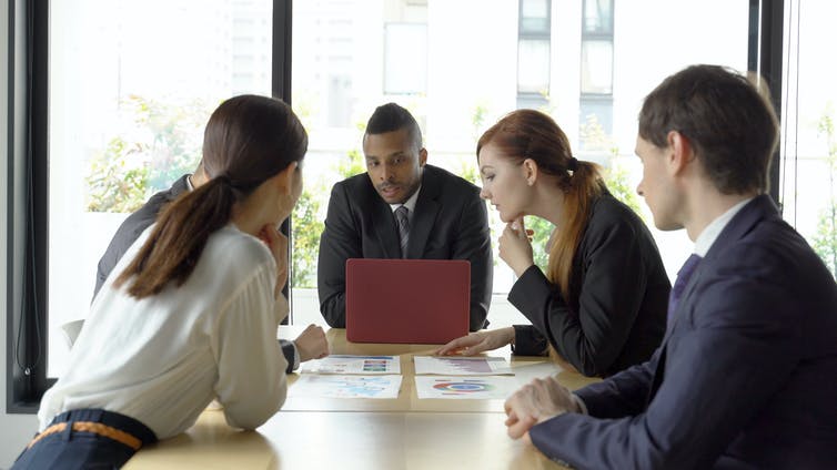 A group of people in business suits having a meeting around a table